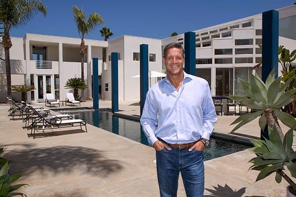 John Assaraf standing beside a pool in his backyard