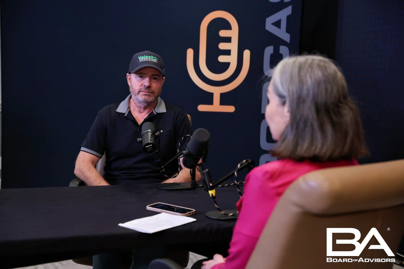 Mike Weiss at a podcast table with two microphones