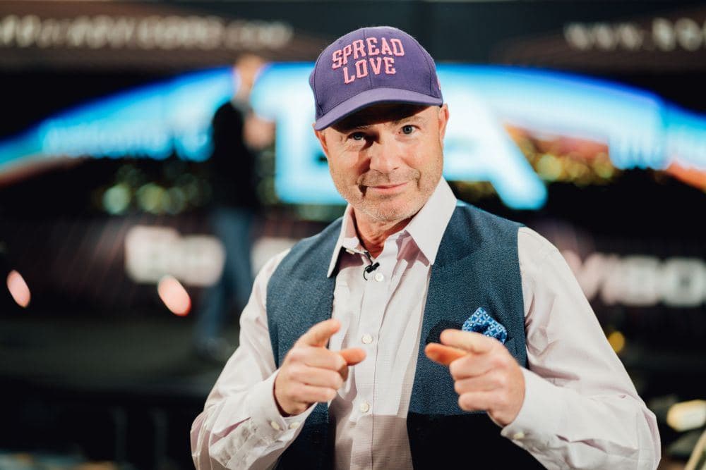 Mike Weiss on stage in a Spread Love cap, pointing at the camera
