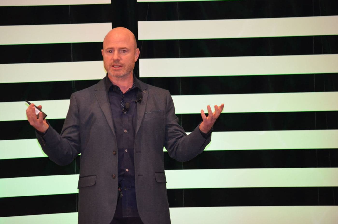 Mike Weiss speaking on stage with open hands