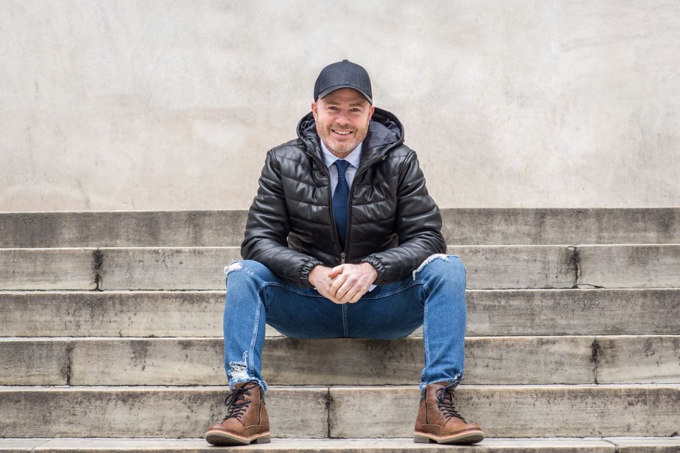 Mike Weiss sitting on concrete steps, smiling