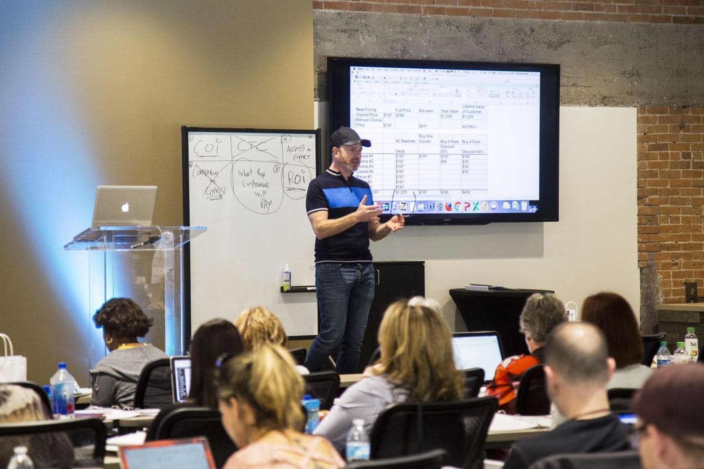 Mike Weiss teaching at a whiteboard in front of a seated class